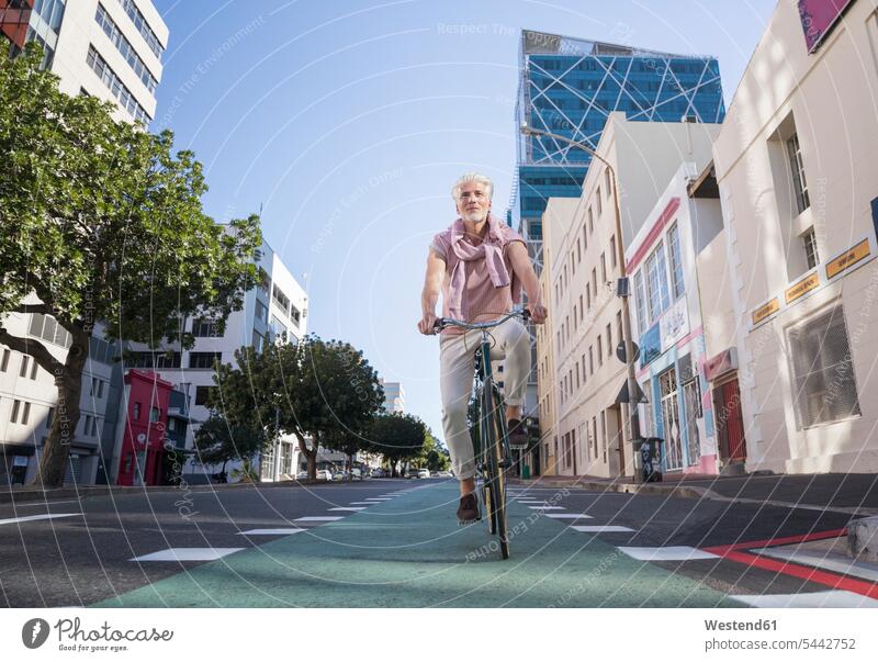 Älterer Mann fährt Fahrrad in der Stadt staedtisch städtisch Männer männlich Bikes Fahrräder Räder Rad radfahren fahrradfahren radeln unterwegs auf Achse