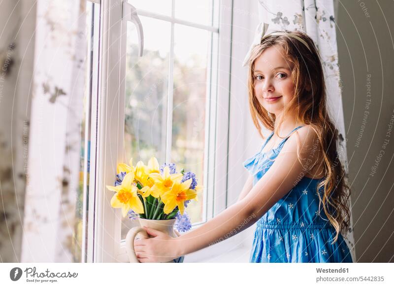 Porträt eines lächelnden Mädchens mit Blumenvase mit Narzissen und Hyazinthen zu Hause weiblich Portrait Porträts Portraits Kind Kinder Kids Mensch Menschen