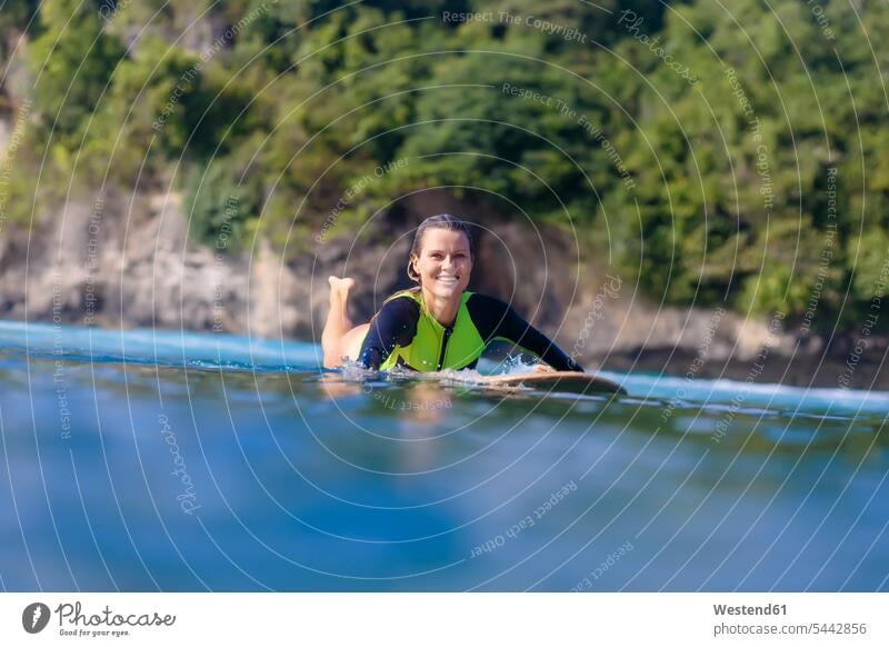 Indonesien, Bali, lächelnde Frau auf dem Surfbrett liegend Surfen Surfing Wellenreiten Meer Meere weiblich Frauen Wassersport Sport Gewässer Erwachsener