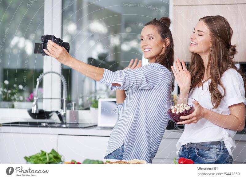Food-Blogger begrüssen ihre Zuschauer in der Küche Selfies Fotokamera Kamera Kameras Leute Menschen People Person Personen erwachsen Erwachsene Frauen weiblich