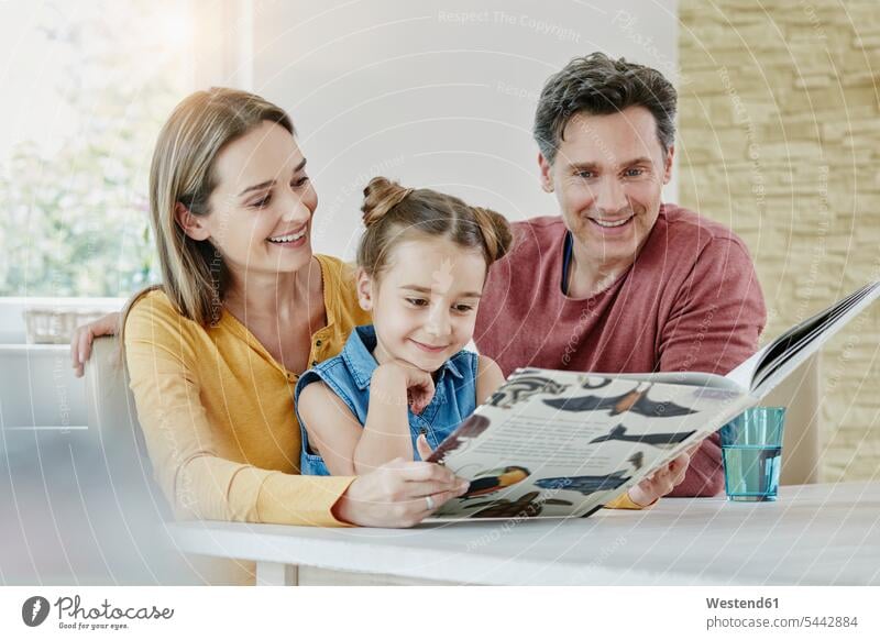 Glückliche Familie zu Hause schaut Bilderbuch an glücklich glücklich sein glücklichsein ansehen Tochter Töchter lesen Lektüre Buch Bücher lächeln Familien
