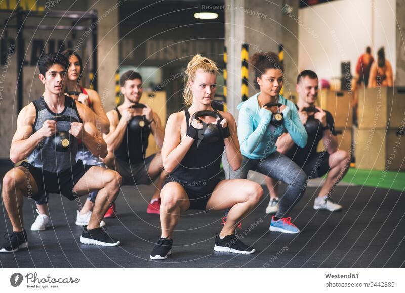 Gruppe junger, fitter Leute beim Heben von Kettlebells im Fitnessstudio Gewicht Gewichte trainieren Fitnessgerät Fitnessgeräte Fitnessgeraete Gesundheit gesund