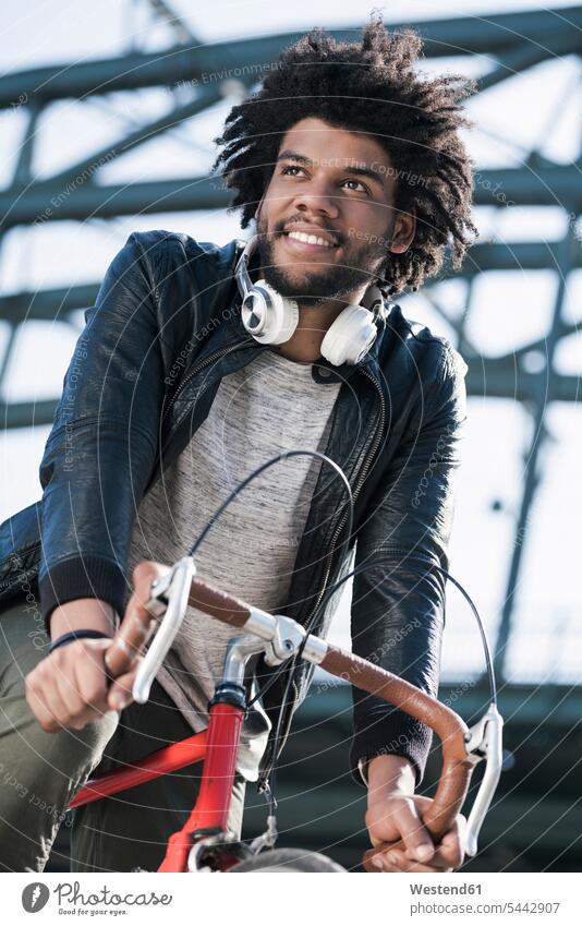 Lächelnder Mann auf dem Fahrrad vor der Brücke Bikes Fahrräder Räder Rad radfahren fahrradfahren radeln lächeln Männer männlich fahrend fahrender fahrendes