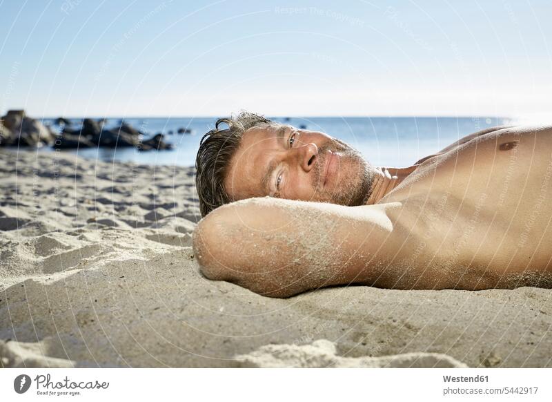 Porträt eines Mannes, der sich am Sandstrand entspannt Meer Meere Strand Beach Straende Strände Beaches Männer männlich Gewässer Wasser Erwachsener erwachsen