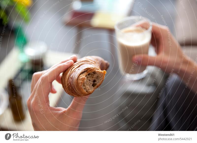 Männerhände halten Croissant und ein Glas Latte Macchiato essen essend Hoernchen Croissants Cornetto Cornettos Hörnchen Gebäck Backware Gebaeck Backwaren