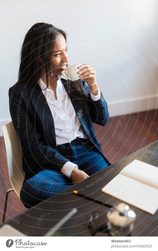 Lächelnde Geschäftsfrau trinkt Kaffee während einer Besprechung im Büro Office Büros Arbeitsplatz Arbeitsstätte Arbeitstelle Geschäftsfrauen Businesswomen