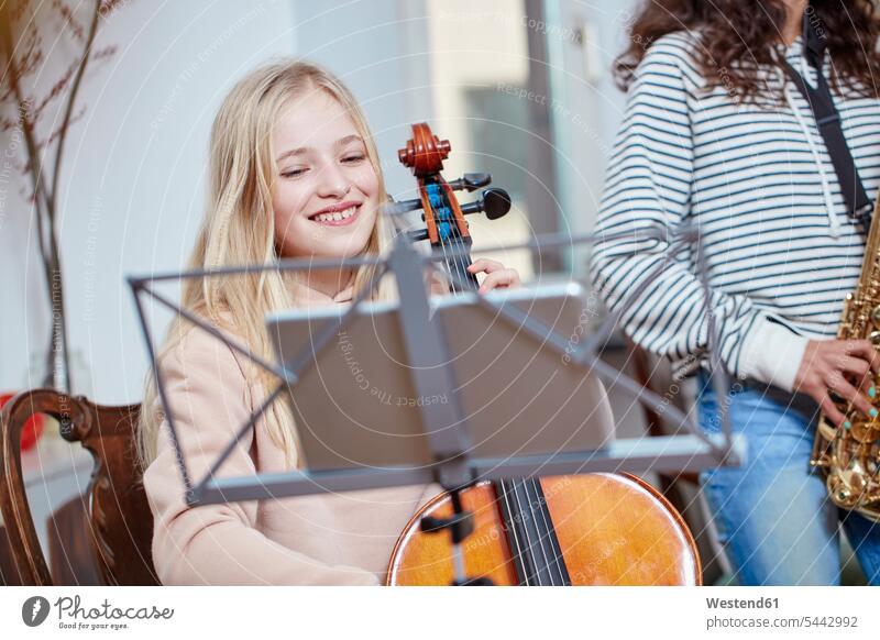 Zwei Mädchen spielen zusammen Cello und Saxophon lächeln weiblich Musik Kind Kinder Kids Mensch Menschen Leute People Personen gemischtrassige Person