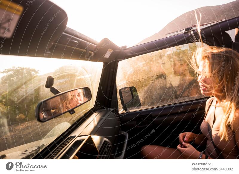 Blonde Frau mit wehendem Haar sitzt bei Sonnenuntergang im Auto weiblich Frauen Sonnenuntergänge blond blonde Haare blondes Haar sitzen sitzend Wagen PKWs