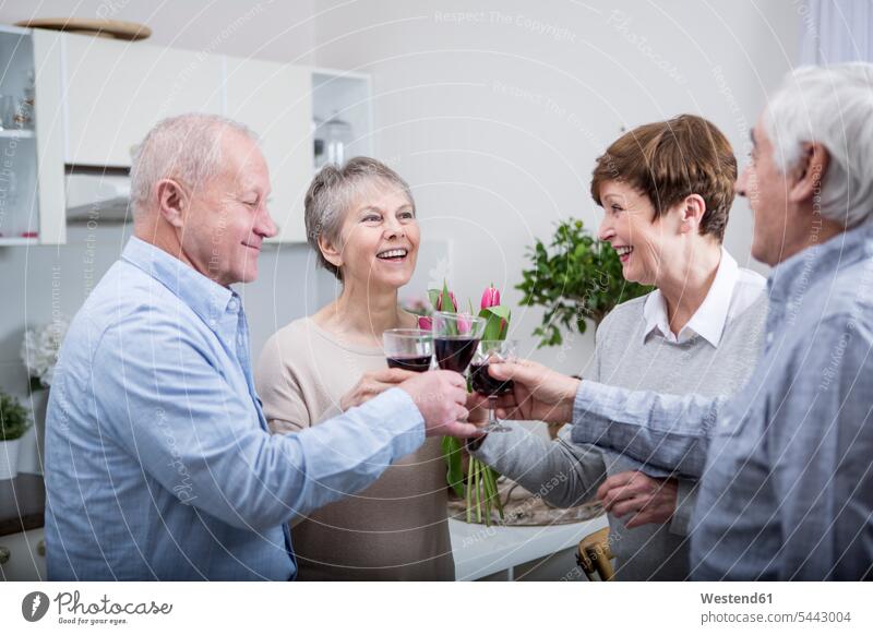 Zwei ältere Paare feiern und stoßen mit Rotwein an trinken anstoßen zuprosten anstossen Senioren alte Rotweine glücklich Glück glücklich sein glücklichsein