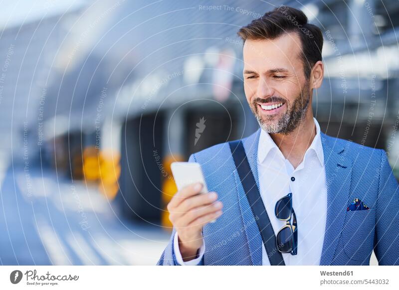 Geschäftsmann benutzt Telefon auf Parkebene im Freien Handy Mobiltelefon Handies Handys Mobiltelefone lächeln Businessmann Businessmänner Geschäftsmänner