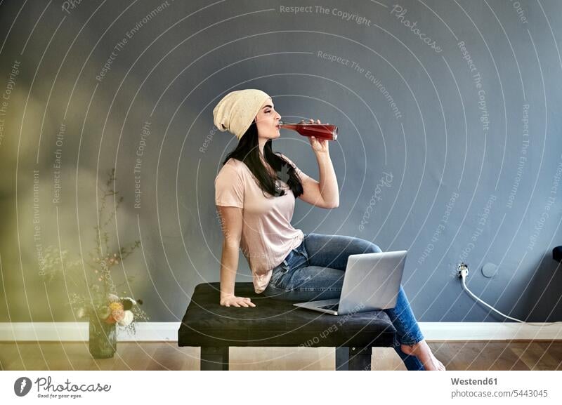 Junge Frau mit Laptop trinkt aus der Flasche sitzen sitzend sitzt Flaschen trinken weiblich Frauen Notebook Laptops Notebooks Erwachsener erwachsen Mensch