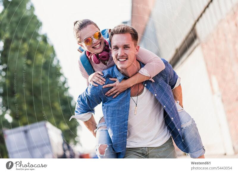 Junger Mann nimmt seine Freundin Huckepack lachen Paar Pärchen Paare Partnerschaft Spaß Spass Späße spassig Spässe spaßig positiv Emotion Gefühl Empfindung