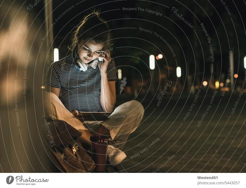 Junge Frau mit Smoothie, die nachts mit Tablette und Kopfhörer auf einer Bank sitzt Nacht weiblich Frauen Erwachsener erwachsen Mensch Menschen Leute People