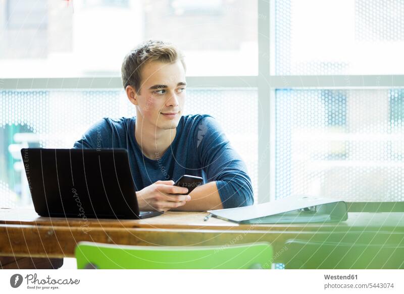 Porträt eines Studenten mit Laptop und Handy in einem Café Portrait Porträts Portraits beobachten zuschauen ansehen Mann Männer männlich Hochschueler