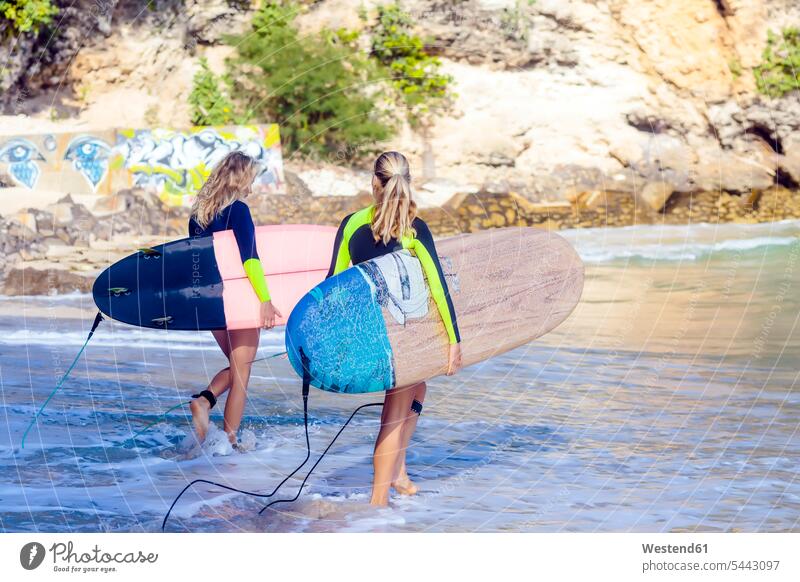 Indonesien, Bali, zwei Frauen tragen Surfbretter auf dem Meer surfboard surfboards Surfen Surfing Wellenreiten Meere weiblich Wassersport Sport Gewässer
