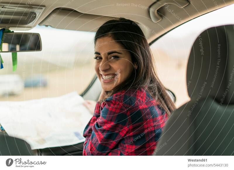 Porträt einer lachenden jungen Frau mit Karte in einem Auto weiblich Frauen Wagen PKWs Automobil Autos Erwachsener erwachsen Mensch Menschen Leute People