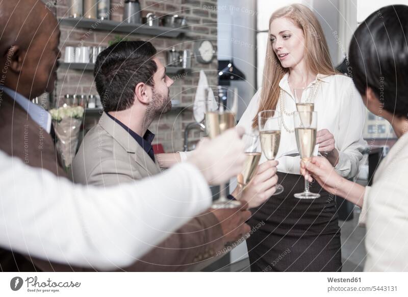 Freunde halten Champagnergläser und unterhalten sich in der Küche Zuhause zu Hause daheim feiern Sekt Freundschaft Kameradschaft Alkohol Alkoholische Getraenke