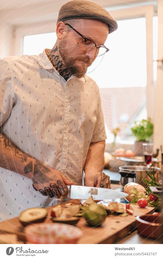 Tätowierter Mann bereitet Essen in der Küche zu kochen schneiden abschneiden kleinschneiden Männer männlich Erwachsener erwachsen Mensch Menschen Leute People
