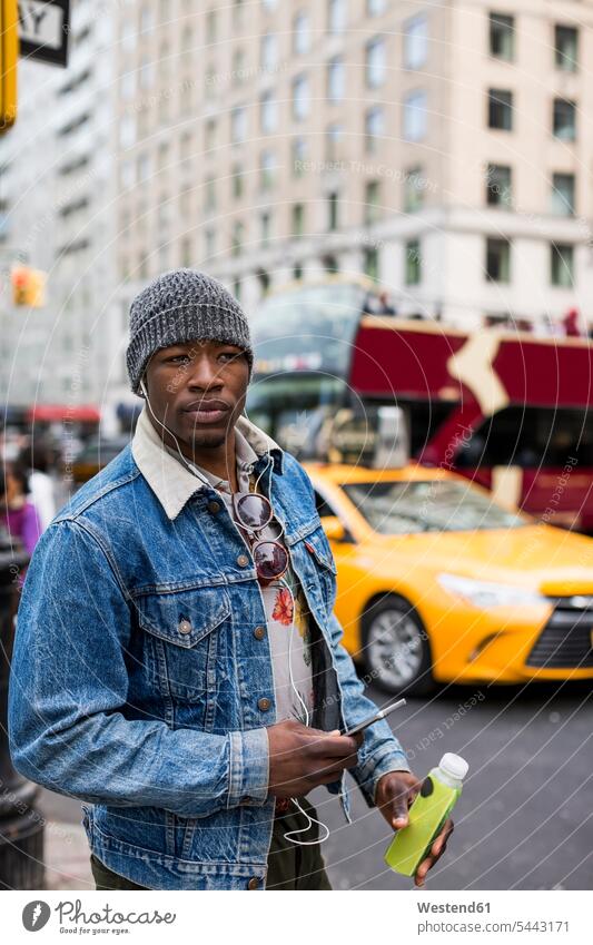 USA, New York City, Manhattan, Porträt eines stilvollen Mannes mit Kopfhörern und Smartphone Männer männlich Portrait Porträts Portraits Erwachsener erwachsen