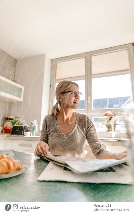 Frau zu Hause sitzt am Tisch mit Zeitung Zeitungen weiblich Frauen Erwachsener erwachsen Mensch Menschen Leute People Personen Zuhause daheim morgens Morgen