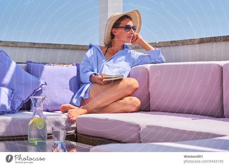 Frau mit Buch entspannt sich auf dem Sonnendeck Glas Trinkgläser Gläser Trinkglas weiblich Frauen Wasser Urlaub Ferien Entspannung relaxen entspannen Bücher