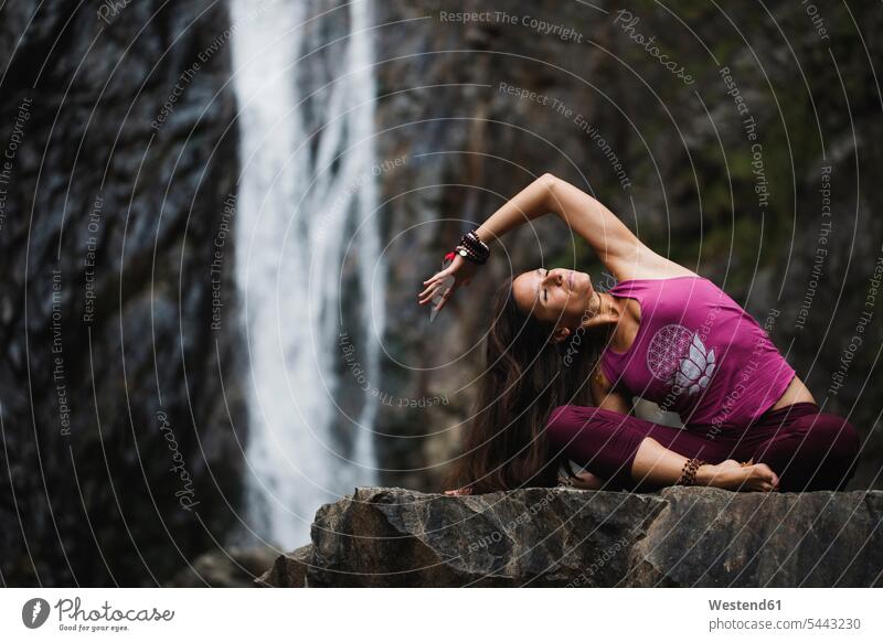 Italien, Lecco, Frau praktiziert Yoga in der Nähe eines Wasserfalls sitzen sitzend sitzt Yoga-Übungen Yogauebungen Yogaübungen Jogauebung Jogauebungen