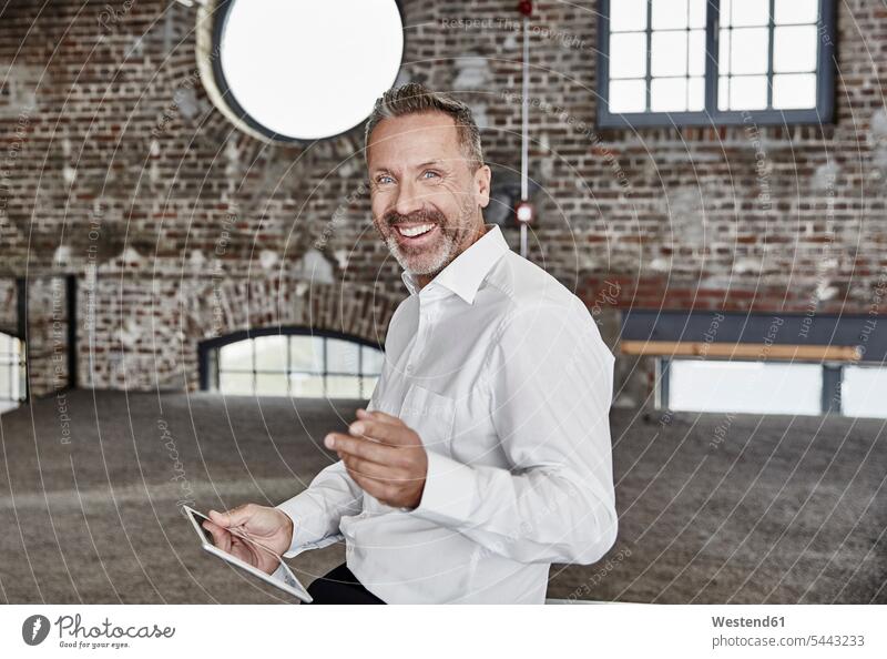 Porträt eines glücklichen Geschäftsmannes mit Tablette in einem Loft Tablet Computer Tablet-PC Tablet PC iPad Tablet-Computer lächeln Businessmann