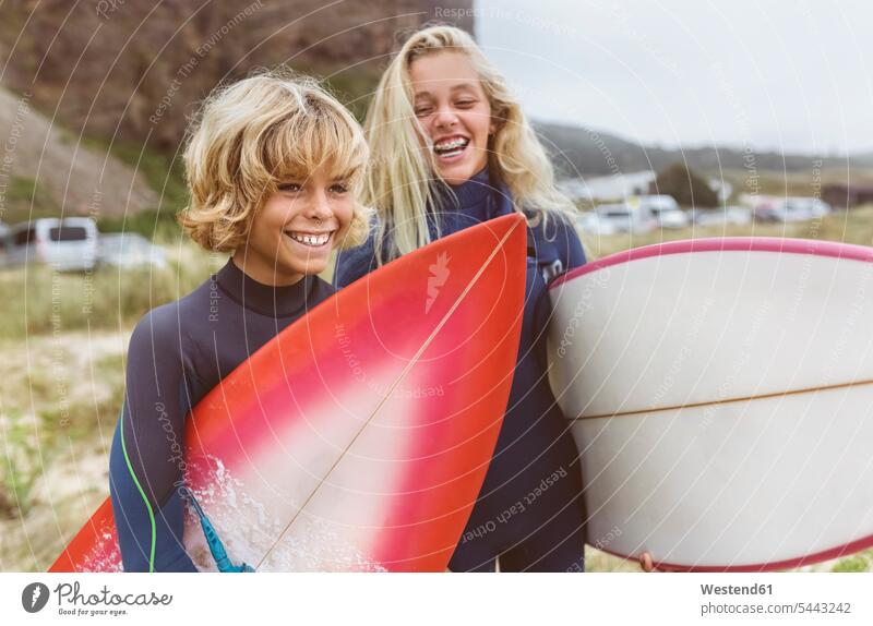 Spanien, Aviles, Porträt von zwei glücklichen jungen Surfern am Strand Wellenreiter Surfbrett Surfbretter surfboard surfboards Teenager Jugendliche