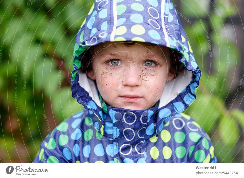 Porträt eines kleinen Jungen mit schmutzigem Gesicht, der bei Regen eine Kapuzenjacke trägt Buben Knabe Knaben männlich Portrait Porträts Portraits Kind Kinder
