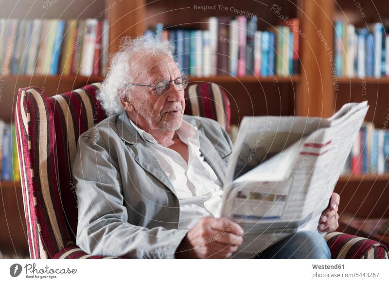 Älterer Mann sitzt in der Bibliothek und liest Zeitung sitzen sitzend lesen Lektüre Sessel Altersheim Altenheim Seniorenheim Zeitungen ältere Männer