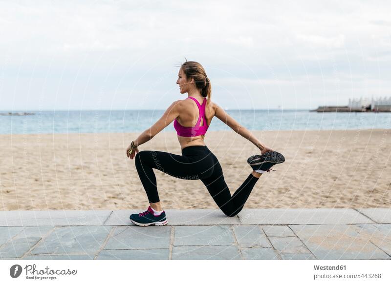 Junge Frau beim Stretching und Aufwärmen für das Training am Strand trainieren Beach Straende Strände Beaches weiblich Frauen dehnen strecken aufwärmen