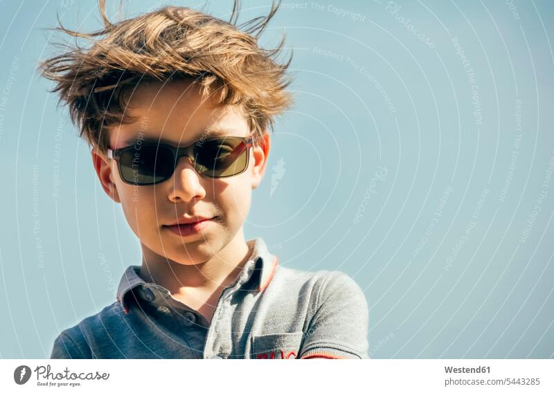 Porträt eines coolen Jungen mit Sonnenbrille und wehendem Haar vor dem Himmel Buben Knabe Knaben männlich Sonnenbrillen Brille Portrait Porträts Portraits Kind