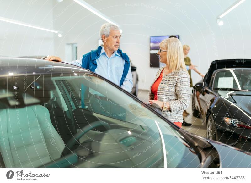 Ehepaar betrachtet Auto in der Werkstatt kaufen Kauf Autohaus Autohäuser Autohaeuser Autohandlung Autohandlungen Wagen PKWs Automobil Autos Autohändler