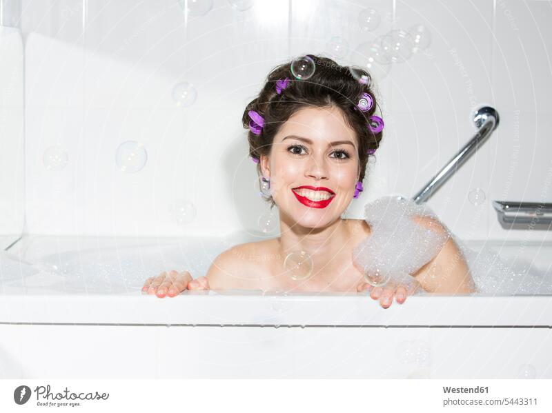 Porträt einer lächelnden jungen Frau mit Lockenwicklern in der Badewanne Portrait Porträts Portraits baden Schaumbad Schaumbaeder Schaumbäder Badewannen