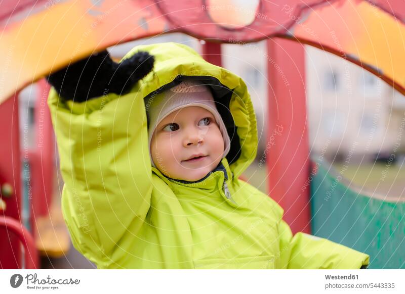 Kleinkind mit Regenjacke auf dem Spielplatz Portrait Porträts Portraits Junge Buben Knabe Jungen Knaben männlich Spielplätze Spielfeld Spielplaetze glücklich