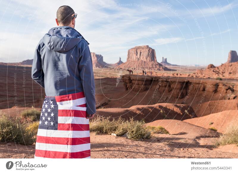 USA, Utah, Rückenansicht eines jungen Mannes mit amerikanischer Flagge im Monument Valley Nationalflagge Nationalflaggen Nationalfahnen Männer männlich Fahnen