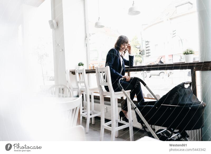 Geschäftsfrau, die vom Café aus arbeitet, mit Kinderwagen auf ihrer Seite sitzen sitzend sitzt Geschäftsfrauen Businesswomen Businessfrauen Businesswoman