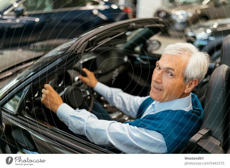 Leitender Mann testet Cabriolet im Autohaus Wagen PKWs Automobil Autos Autohäuser Autohaeuser Autohandlung Autohandlungen testen kaufen Kauf Kunde Kunden