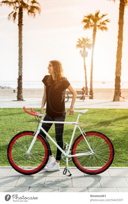Lächelnde junge Frau mit Fixie-Bike Fahrrad Bikes Fahrräder Räder Rad weiblich Frauen Raeder Verkehrswesen Transportwesen Erwachsener erwachsen Mensch Menschen