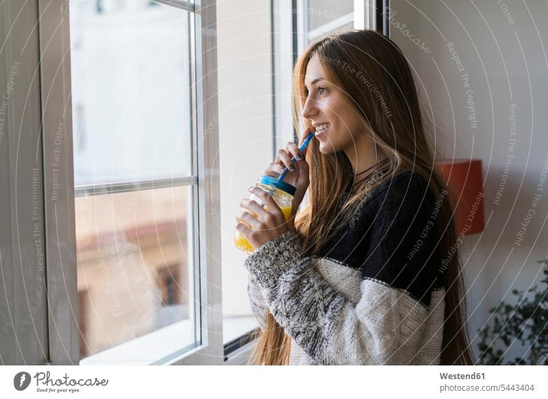 Junge Frau am Fenster trinkt selbstgemachtes Getränk weiblich Frauen lächeln trinken Erwachsener erwachsen Mensch Menschen Leute People Personen Getraenk