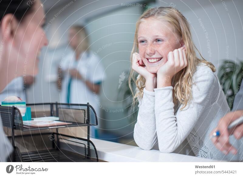 Glückliches Mädchen steht am Krankenhausempfang Patientin Patientinnen Arzt Doktoren Ärzte Kliniken Krankenhäuser Krankenhaeuser lachen Kranker Patienten
