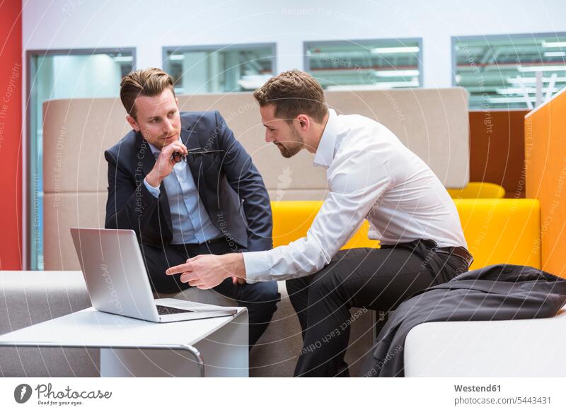 Geschäftsleute sitzen in der Gesprächsgrube und diskutieren vor dem Laptop Kollegen Arbeitskollegen Sitzecke sitzend sitzt Laptop benutzen Laptop benützen