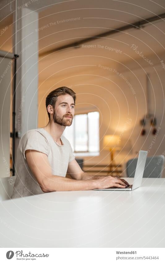 Porträt eines jungen Mannes, der auf einem Laptop in einem Loft arbeitet Notebook Laptops Notebooks Männer männlich Computer Rechner Erwachsener erwachsen