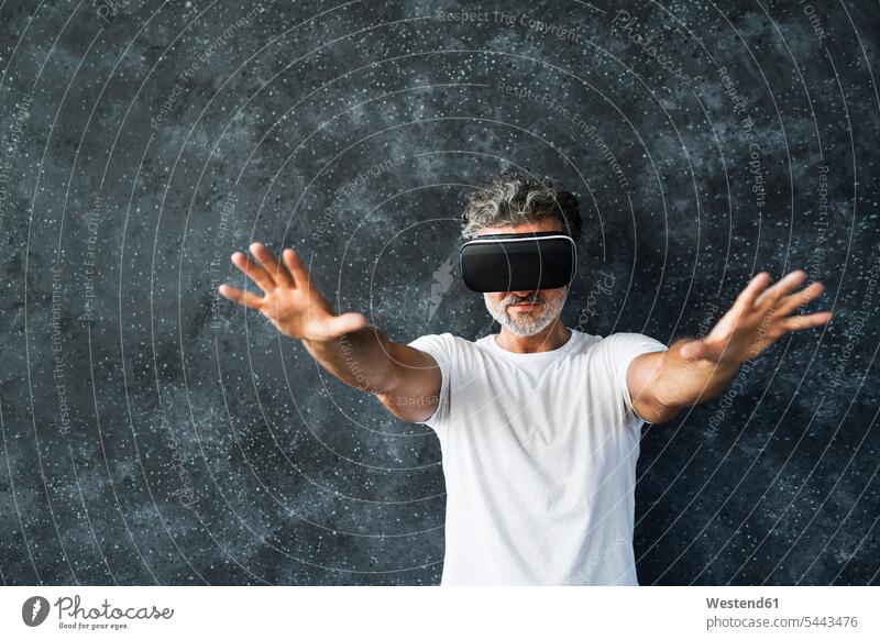 Reifer Mann mit VR-Brille, der die Hände ausstreckt T-Shirt T-Shirts hindurchsehen ausstrecken Digitalisierung interaktiv Interaktivität Orientierungslosigkeit