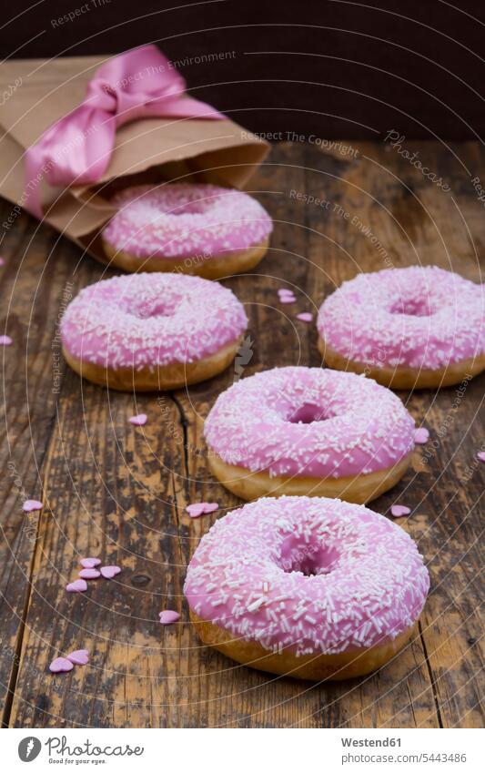 Doughnuts mit rosa Glasur und Zuckergranulat auf Holz Food and Drink Lebensmittel Essen und Trinken Nahrungsmittel Zuckerguss Zuckerguß Streudekor süß Süßes