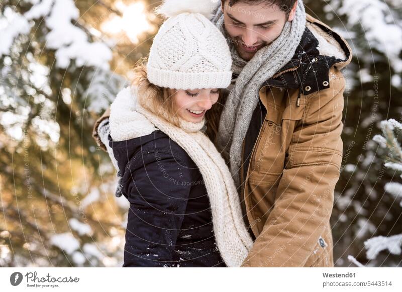 Glückliches junges Paar im schneebedeckten Winterwald Pärchen Paare Partnerschaft Mensch Menschen Leute People Personen lachen winterlich Winterzeit Schnee