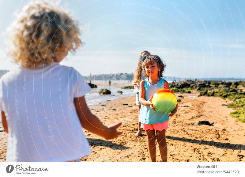 Mit Ball spielende Kinder am Strand Mädchen weiblich Beach Straende Strände Beaches Kids Mensch Menschen Leute People Personen Freunde stehen stehend steht