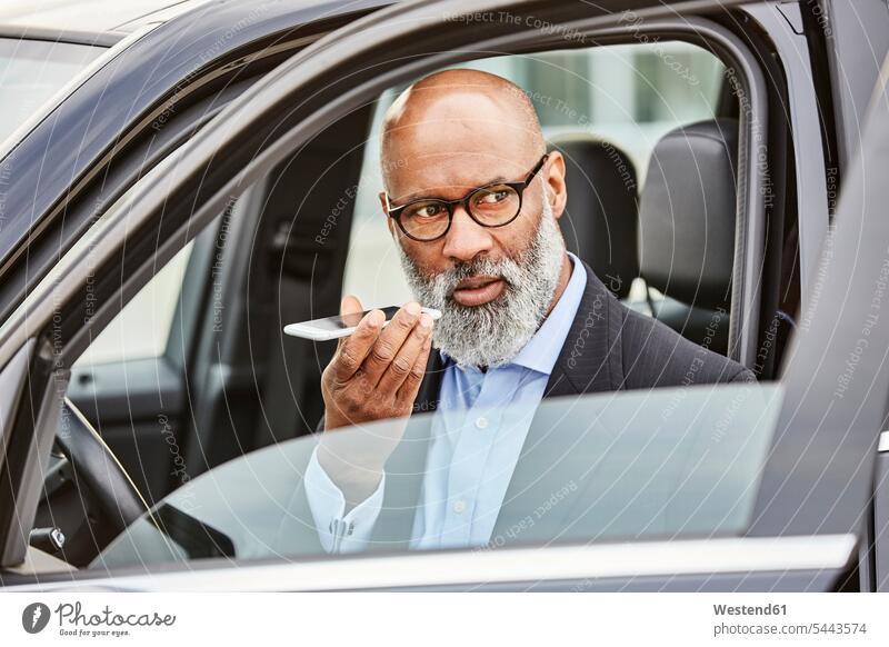 Geschäftsmann sitzt im Auto und benutzt ein Smartphone unterwegs auf Achse in Bewegung iPhone Smartphones Handy Mobiltelefon Handies Handys Mobiltelefone