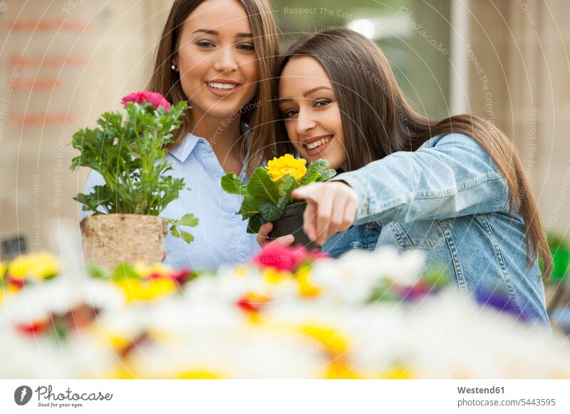 Freundinnen wählen Topfpflanzen am Blumenstand zeigen mit dem Finger zeigen deuten gärtnern Gartenarbeit Gartenbau ansehen Gemeinsam Zusammen Miteinander lachen