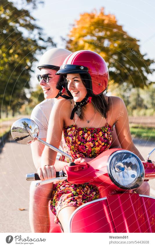 Glückliches junges Paar fährt Motorroller auf der Landstraße Roller Piaggio glücklich glücklich sein glücklichsein fahren Pärchen Paare Partnerschaft